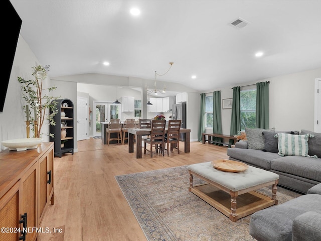 living room featuring light wood-type flooring, lofted ceiling, and an inviting chandelier