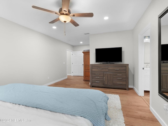 bedroom with light wood-type flooring, ceiling fan, and connected bathroom