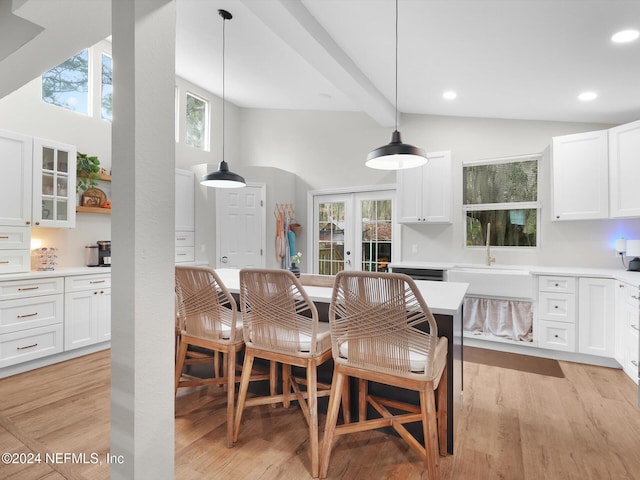 dining room featuring a wealth of natural light, beam ceiling, light wood-type flooring, and french doors