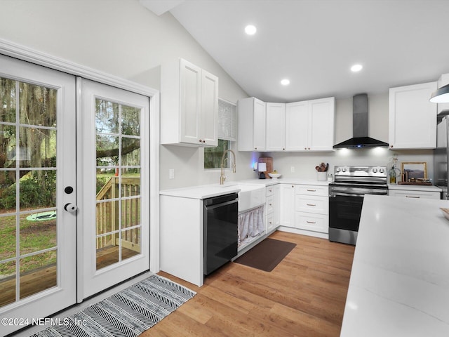 kitchen featuring wall chimney exhaust hood, stainless steel range with electric cooktop, lofted ceiling, white cabinets, and dishwasher