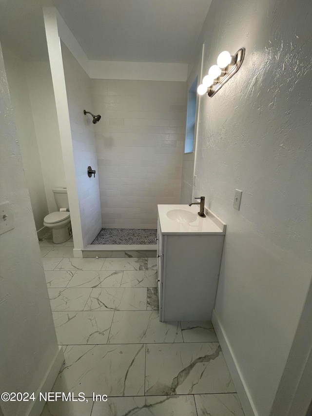 bathroom with toilet, vanity, and a tile shower