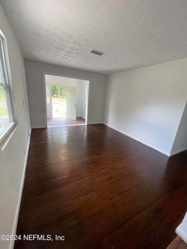 spare room with dark wood-type flooring and a textured ceiling