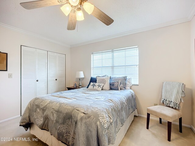 carpeted bedroom featuring ceiling fan, a closet, and ornamental molding