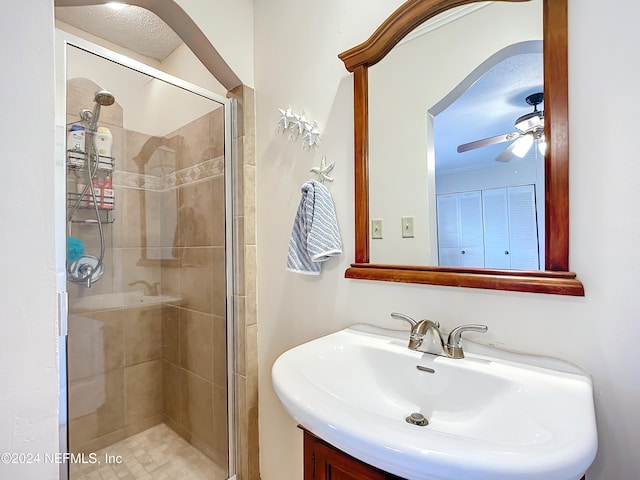 bathroom with sink, ceiling fan, and a shower with shower door