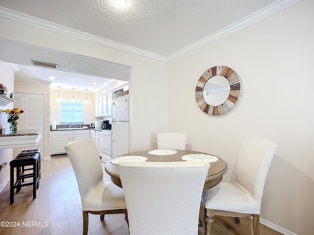 dining space with ornamental molding, light hardwood / wood-style floors, a textured ceiling, and sink