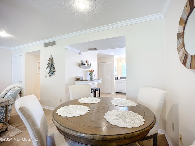 dining room with wood-type flooring, a textured ceiling, and crown molding