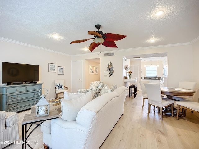 living room with ceiling fan, a textured ceiling, light hardwood / wood-style flooring, and crown molding