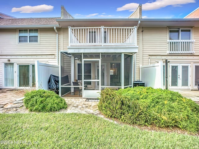 rear view of house with a sunroom, a balcony, and a yard