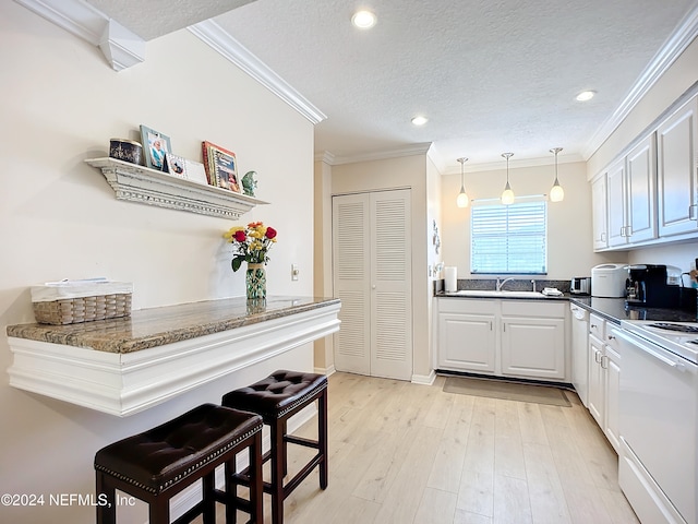 kitchen featuring white cabinetry, kitchen peninsula, ornamental molding, a kitchen breakfast bar, and white appliances