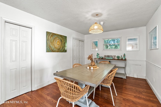 dining area with dark wood-type flooring and a textured ceiling