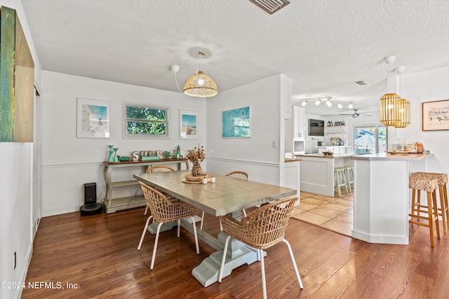 dining space with hardwood / wood-style flooring, ceiling fan, and a textured ceiling