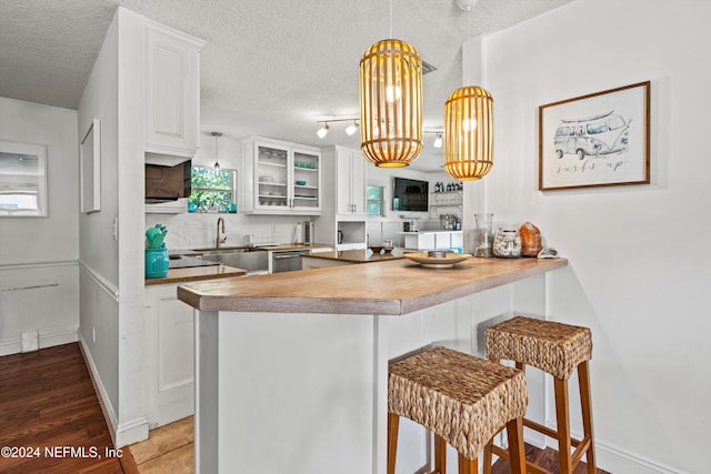 kitchen with white cabinets, a textured ceiling, and kitchen peninsula