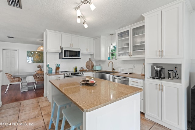 kitchen featuring stainless steel appliances, white cabinets, and a center island