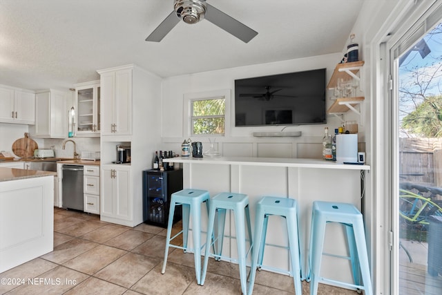 kitchen with stainless steel dishwasher, a breakfast bar area, white cabinetry, and kitchen peninsula