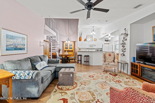 living room with light hardwood / wood-style floors and ceiling fan with notable chandelier