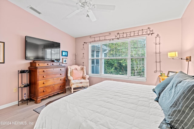 bedroom with ceiling fan, light hardwood / wood-style floors, and vaulted ceiling