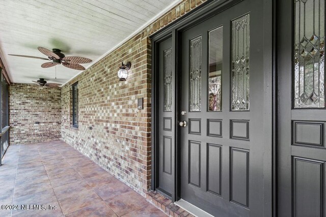 view of exterior entry featuring a porch and ceiling fan