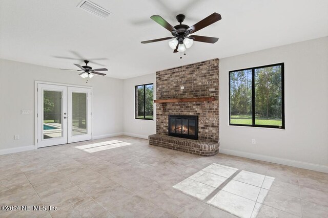 unfurnished living room featuring french doors, ceiling fan, and a fireplace