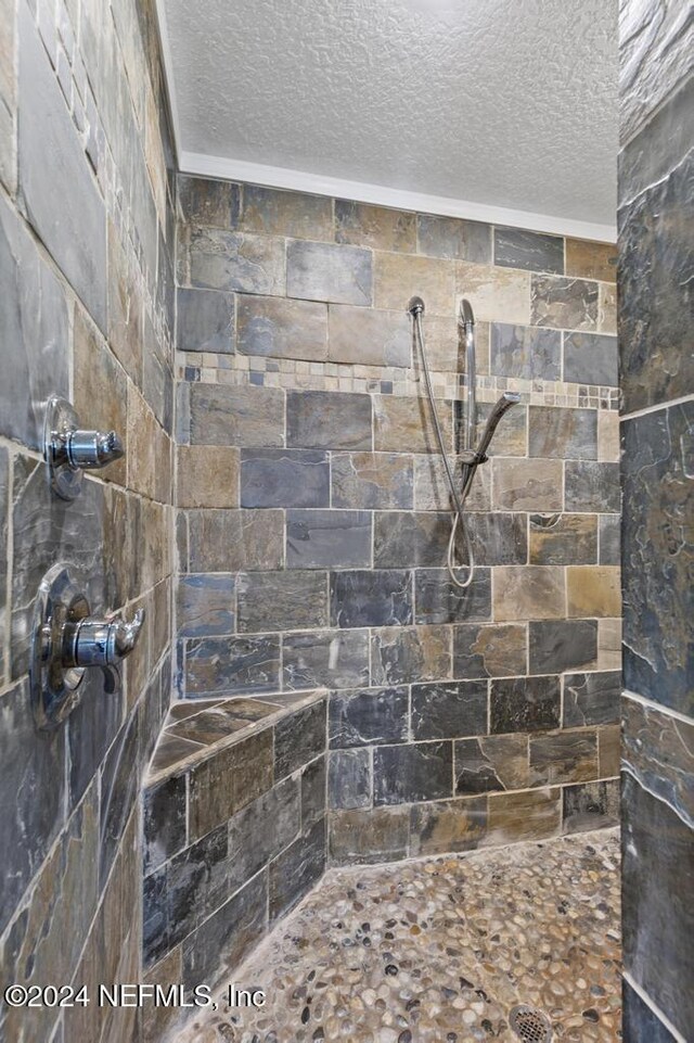 bathroom with a textured ceiling and a tile shower