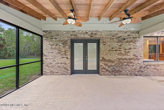 unfurnished sunroom with beamed ceiling, french doors, wooden ceiling, and ceiling fan