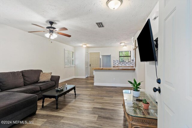 living room featuring wood-type flooring, ceiling fan, and a textured ceiling