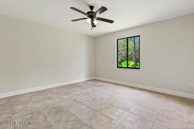 empty room with ceiling fan and light tile patterned floors