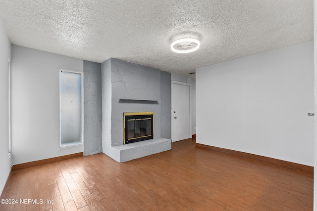 unfurnished living room featuring a large fireplace, a textured ceiling, and hardwood / wood-style flooring