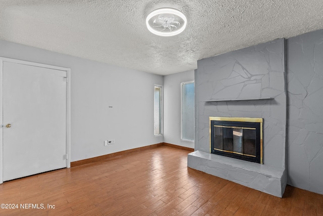 unfurnished living room featuring a fireplace, a textured ceiling, and hardwood / wood-style flooring