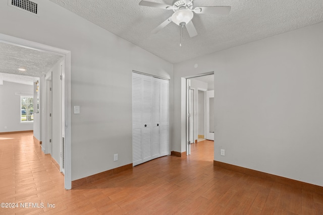 unfurnished bedroom featuring hardwood / wood-style flooring, ceiling fan, a textured ceiling, and a closet