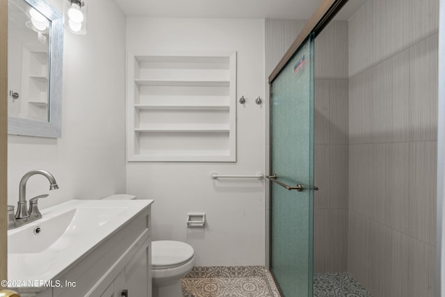 bathroom with tile patterned floors, vanity, toilet, and a shower with door