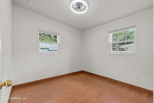 spare room with a healthy amount of sunlight, wood-type flooring, and a textured ceiling