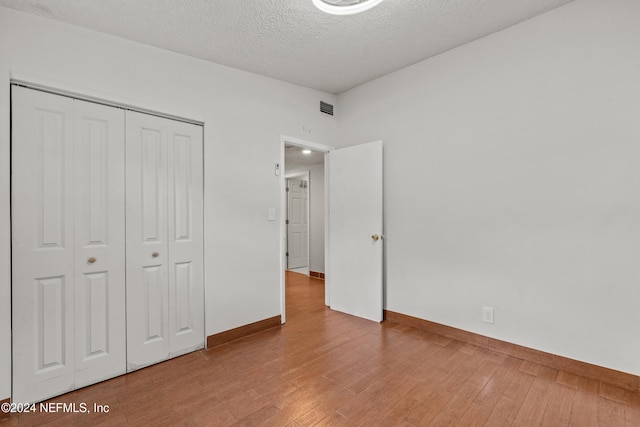 unfurnished bedroom with hardwood / wood-style flooring, a textured ceiling, and a closet