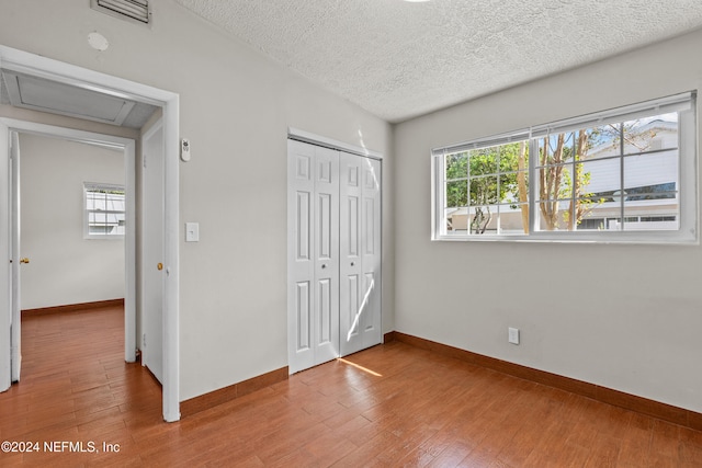 unfurnished bedroom featuring hardwood / wood-style floors, a textured ceiling, and a closet