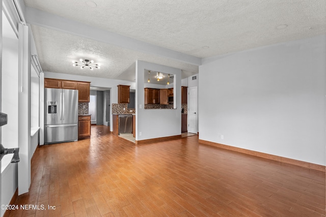 unfurnished living room with a textured ceiling and light hardwood / wood-style floors