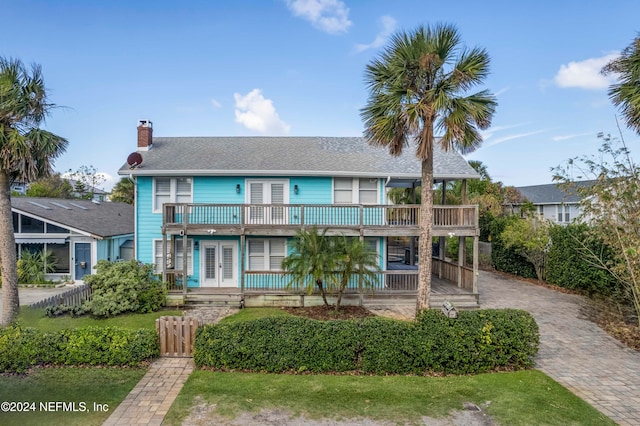 view of front of home featuring french doors, a balcony, covered porch, and a front yard