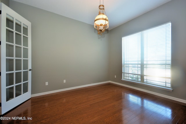 unfurnished room featuring dark hardwood / wood-style floors and an inviting chandelier