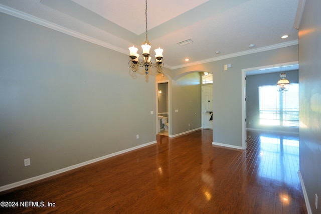 empty room featuring a chandelier, dark hardwood / wood-style flooring, and ornamental molding