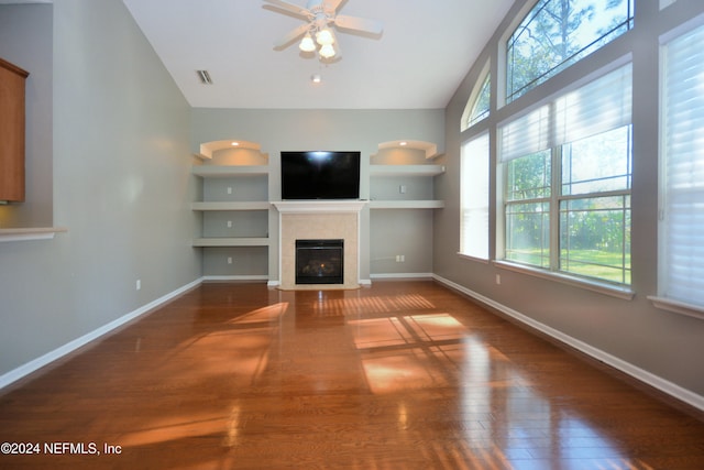 unfurnished living room with ceiling fan, built in features, dark hardwood / wood-style floors, and vaulted ceiling