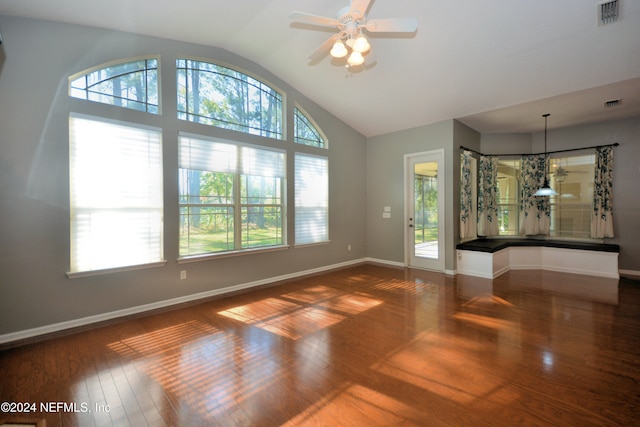 unfurnished living room with ceiling fan with notable chandelier, dark hardwood / wood-style floors, and vaulted ceiling