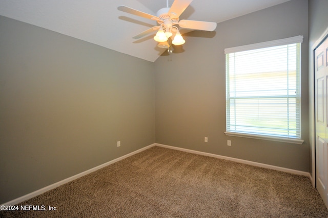 carpeted spare room with ceiling fan, plenty of natural light, and vaulted ceiling