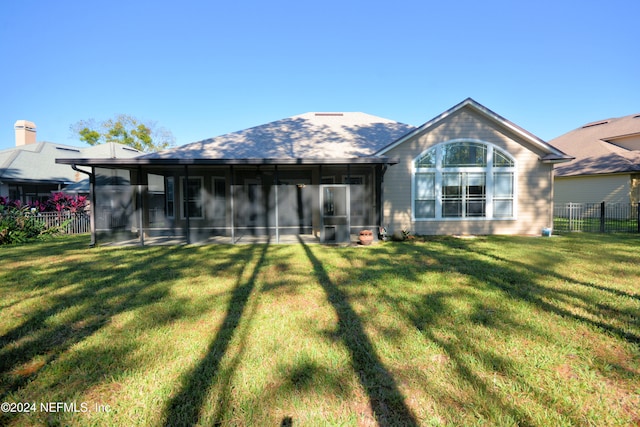 rear view of property featuring a sunroom and a lawn