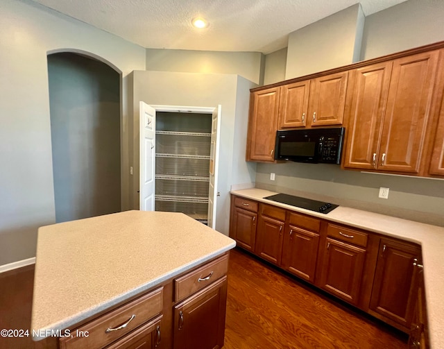 kitchen with a textured ceiling, dark wood-type flooring, and black appliances