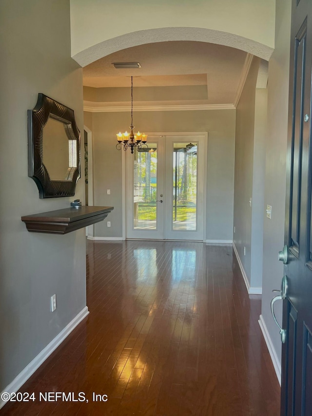 interior space with dark hardwood / wood-style flooring, french doors, crown molding, and a chandelier