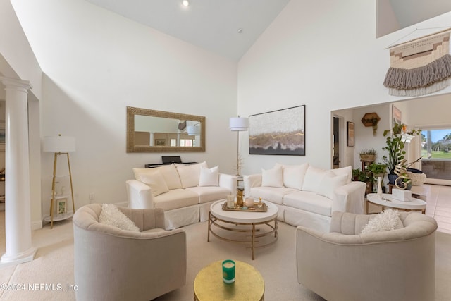 living room featuring high vaulted ceiling, light colored carpet, and ornate columns