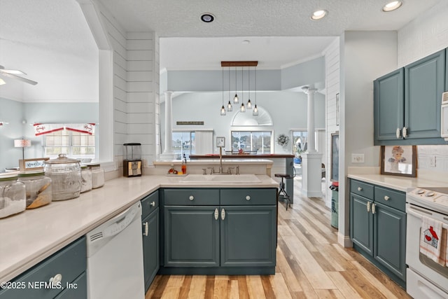 kitchen with sink, white appliances, hanging light fixtures, and kitchen peninsula