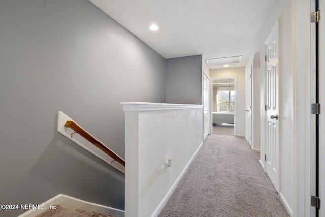 hall with a textured ceiling and light carpet