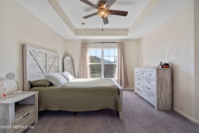 bedroom featuring a tray ceiling, a textured ceiling, ceiling fan, and carpet floors