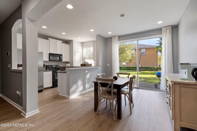 dining area featuring a textured ceiling and light hardwood / wood-style flooring