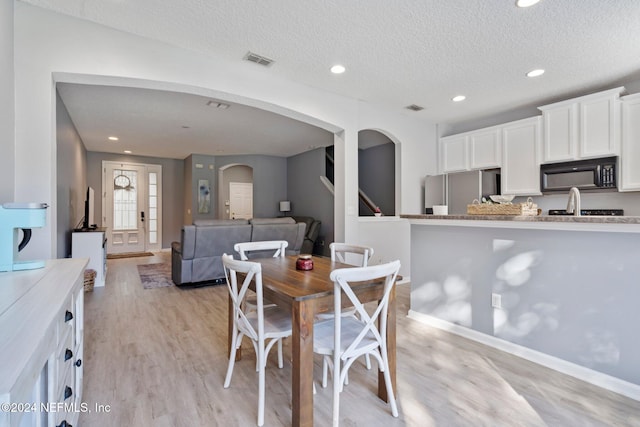 dining space with light hardwood / wood-style floors and a textured ceiling