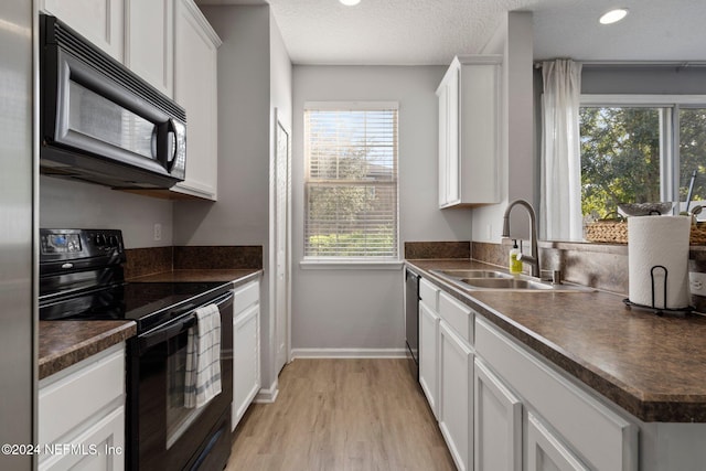 kitchen with black appliances, sink, a healthy amount of sunlight, and white cabinets